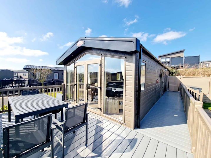 Outside the front of the lodge, showing the spacious decking and quality garden furniture.