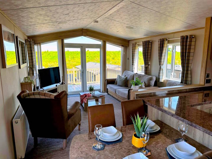 Inside the lodge showing the open plan living, viewing the sitting area and TV from the dining area.